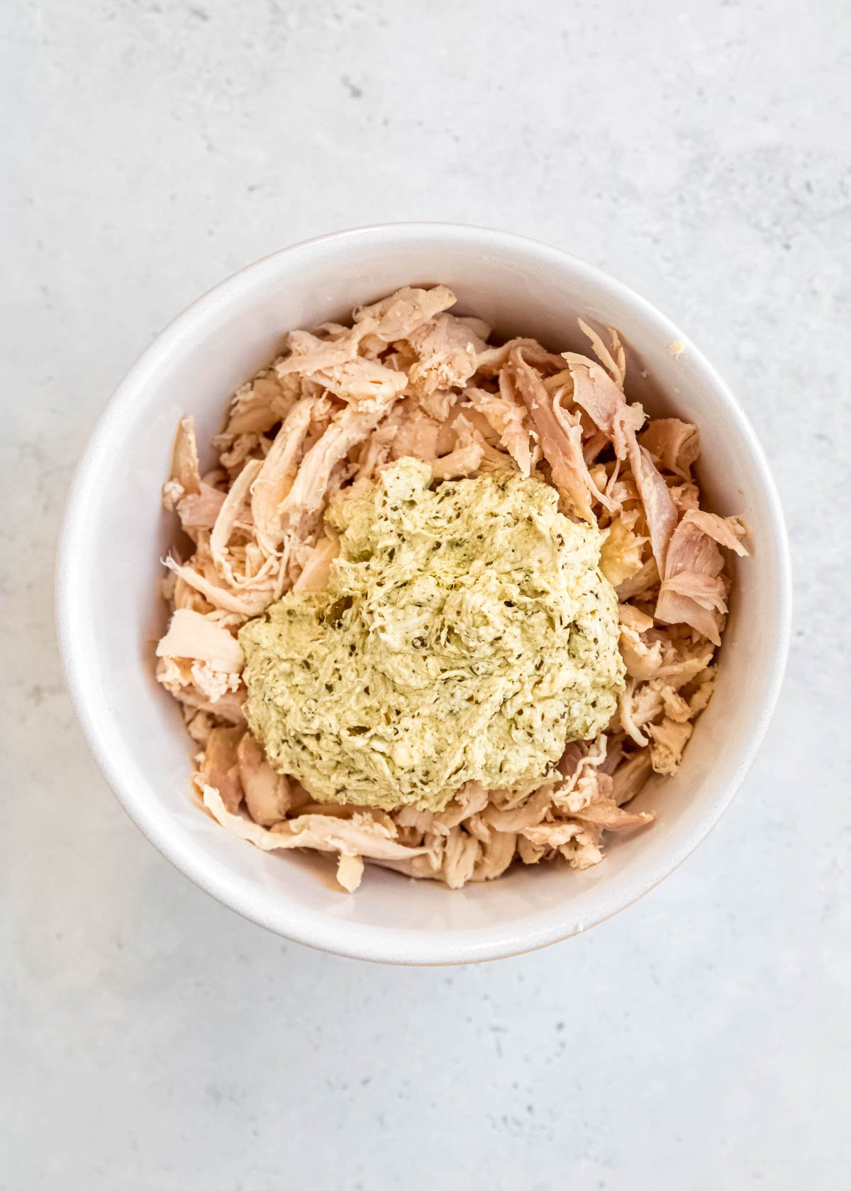 shredded chicken in a bowl with creamy pesto