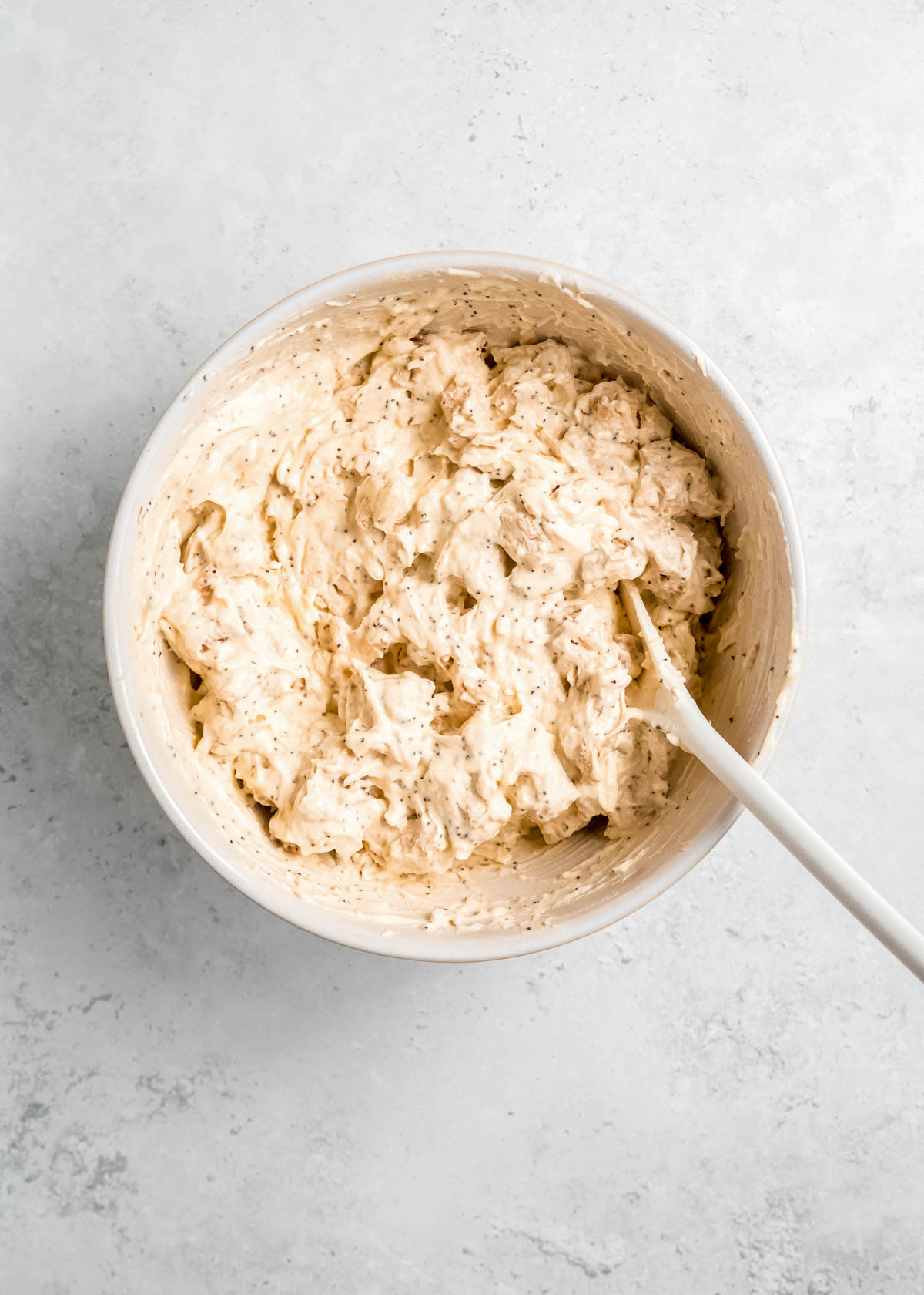 chicken being added to casserole sauce in white mixing bowl