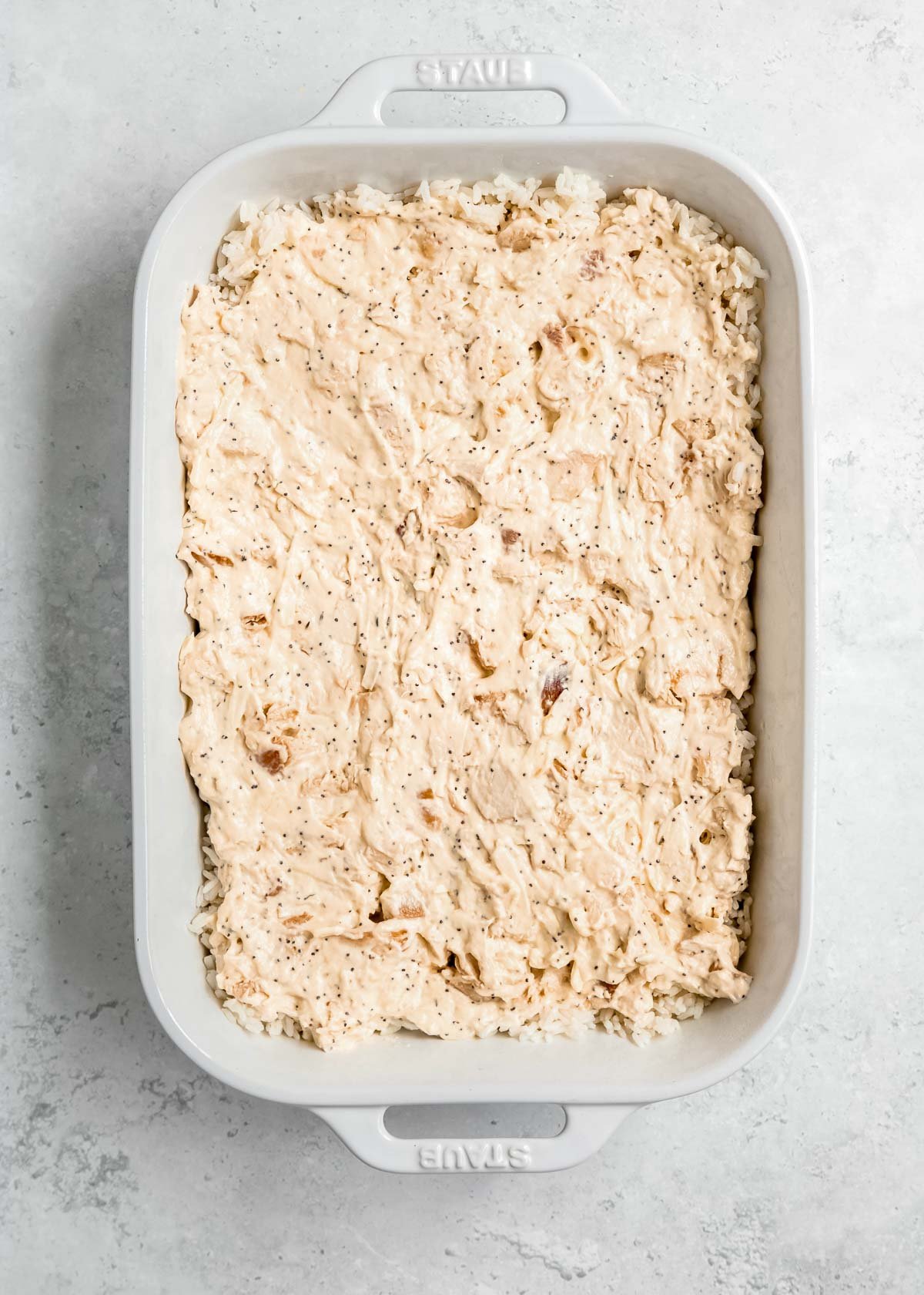 chicken and sauce being added to baking dish with rice