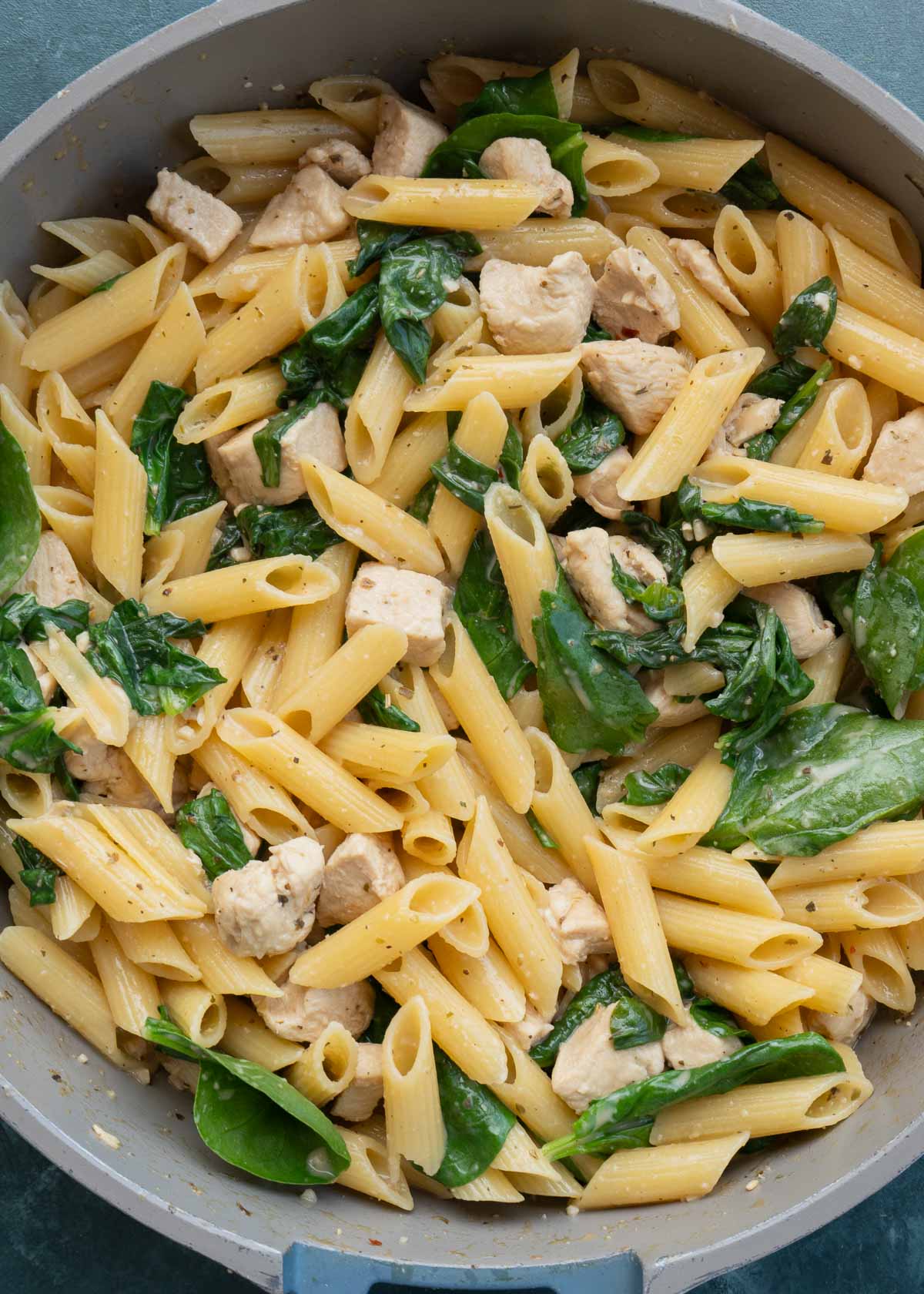 cooked spinach, pasta and chicken in skillet