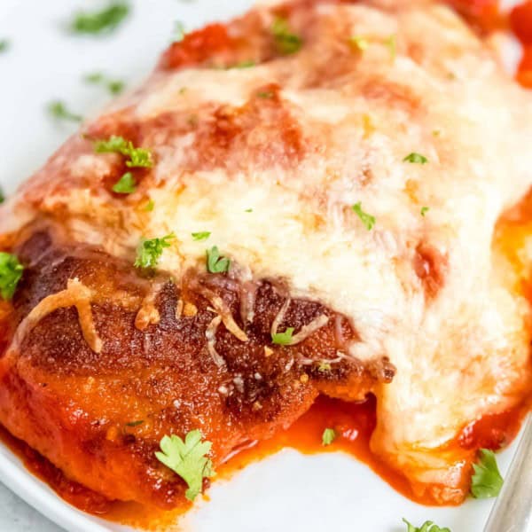 close up image of chicken parmesan on white plate