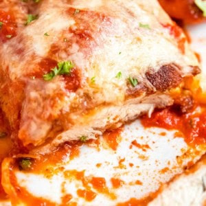 close up image of sliced chicken parmesan on white plate