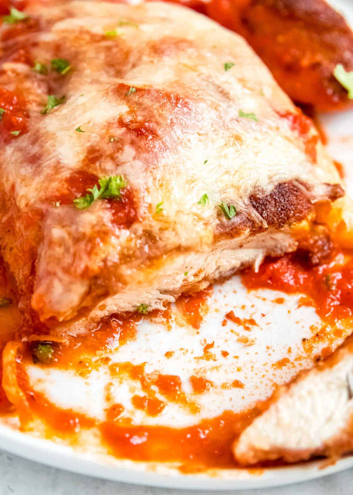 close up image of sliced chicken parmesan on white plate