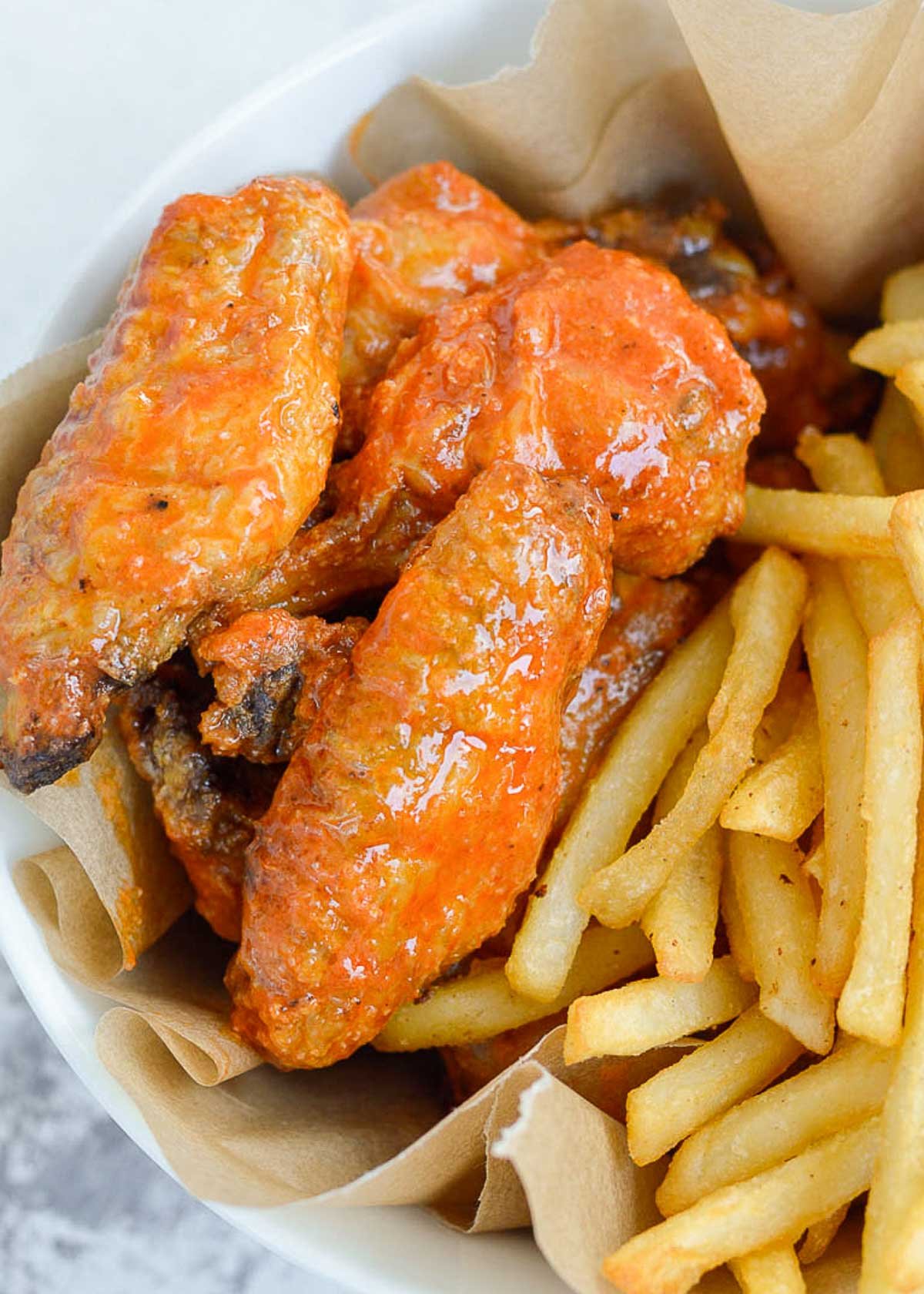 easy air fryer chicken wings in buffalo sauce with a side of french fries