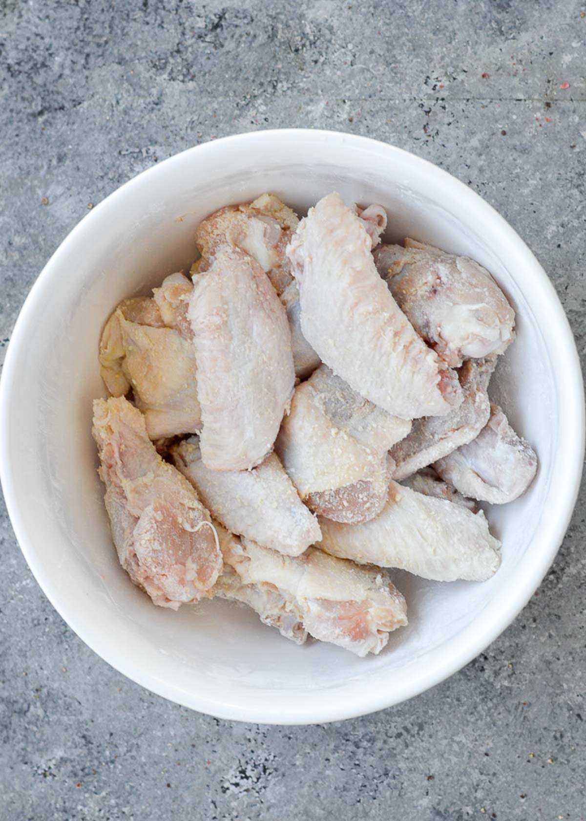 party wings in a white bowl coated in baking powder