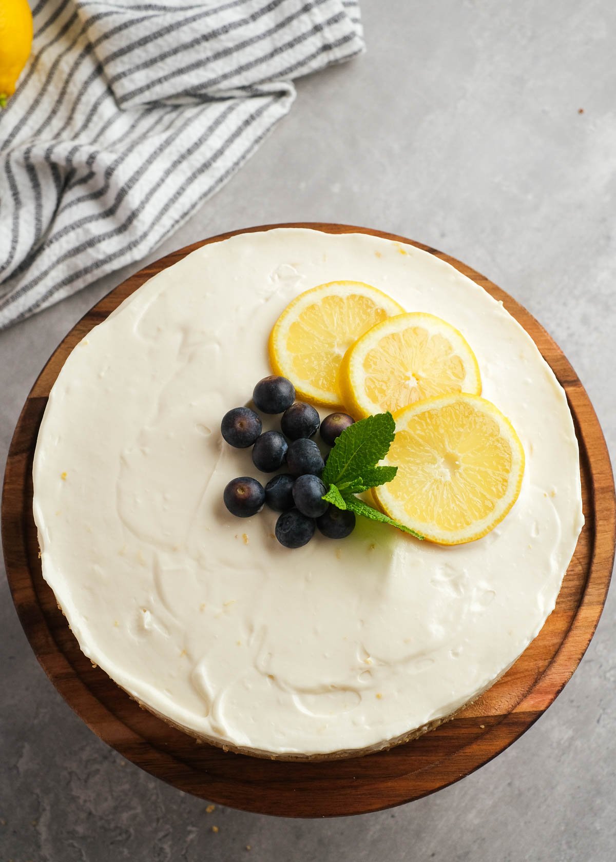 a no-bake lemon cheesecake topped with blueberries, mint leaves, and slices of lemon