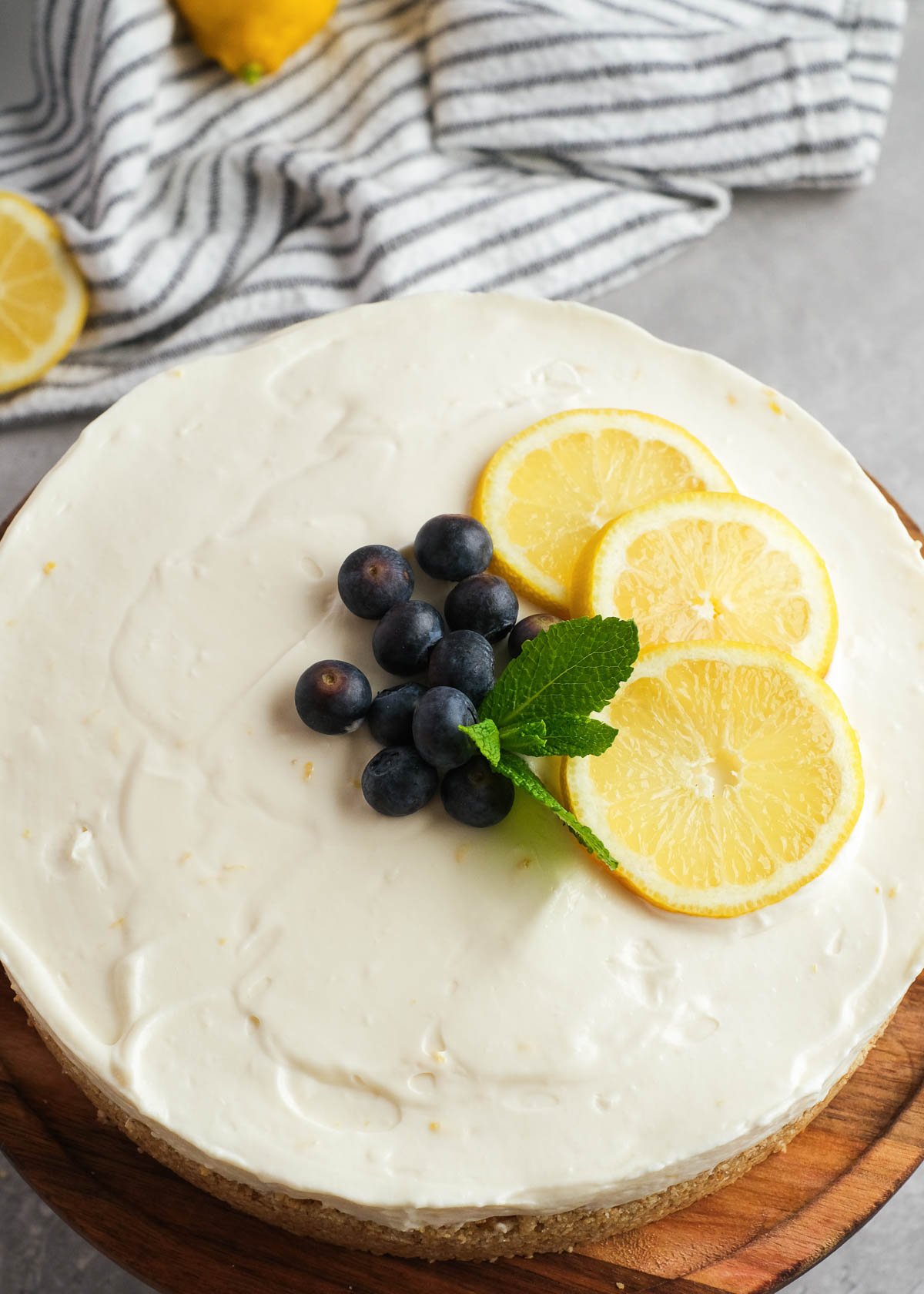 closeup view of creamy no-bake lemon cheesecake garnished with blueberries and lemons