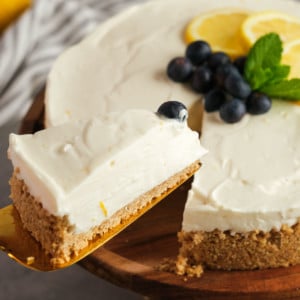 a serving spatula grabbing a slice of easy lemon cheesecake topped with blueberries