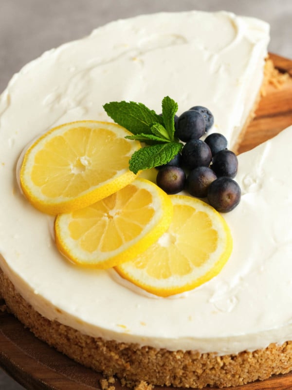 lemon slices, mint leaves, and fresh blueberries atop a creamy lemon cheesecake with a graham cracker crust