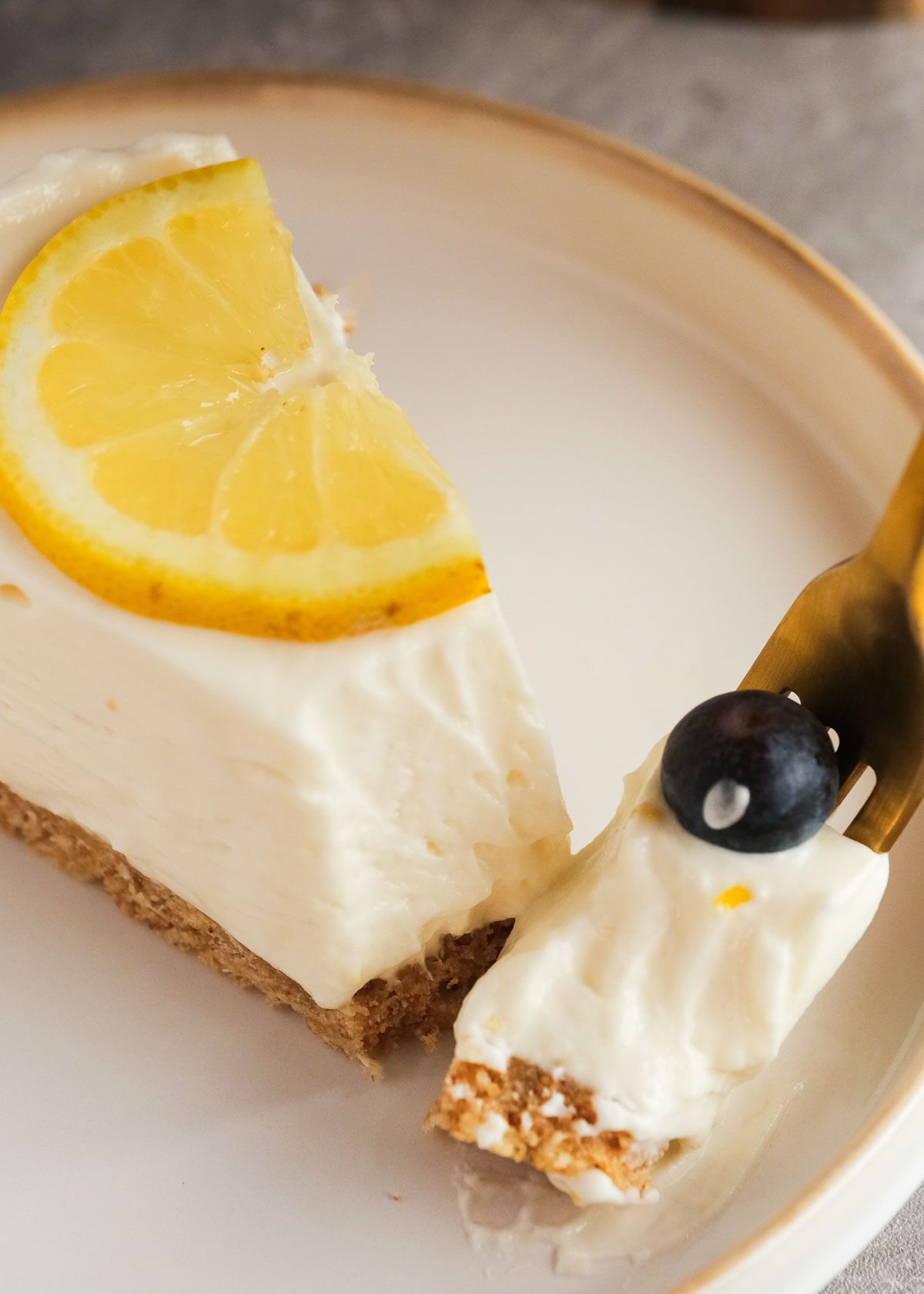 a fork taking a creamy bite of the luscious lemon cheesecake