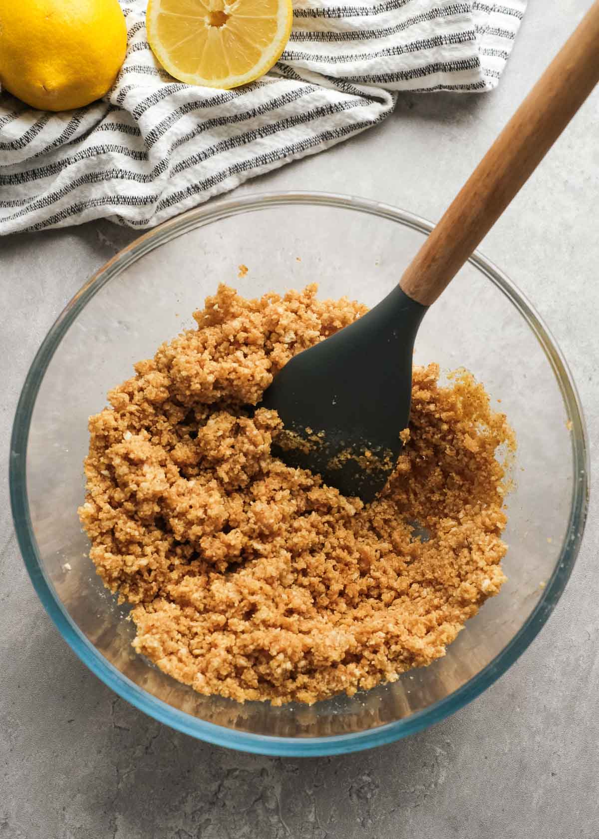 graham cracker crumbs being mixed with sugar and butter in a glass bowl