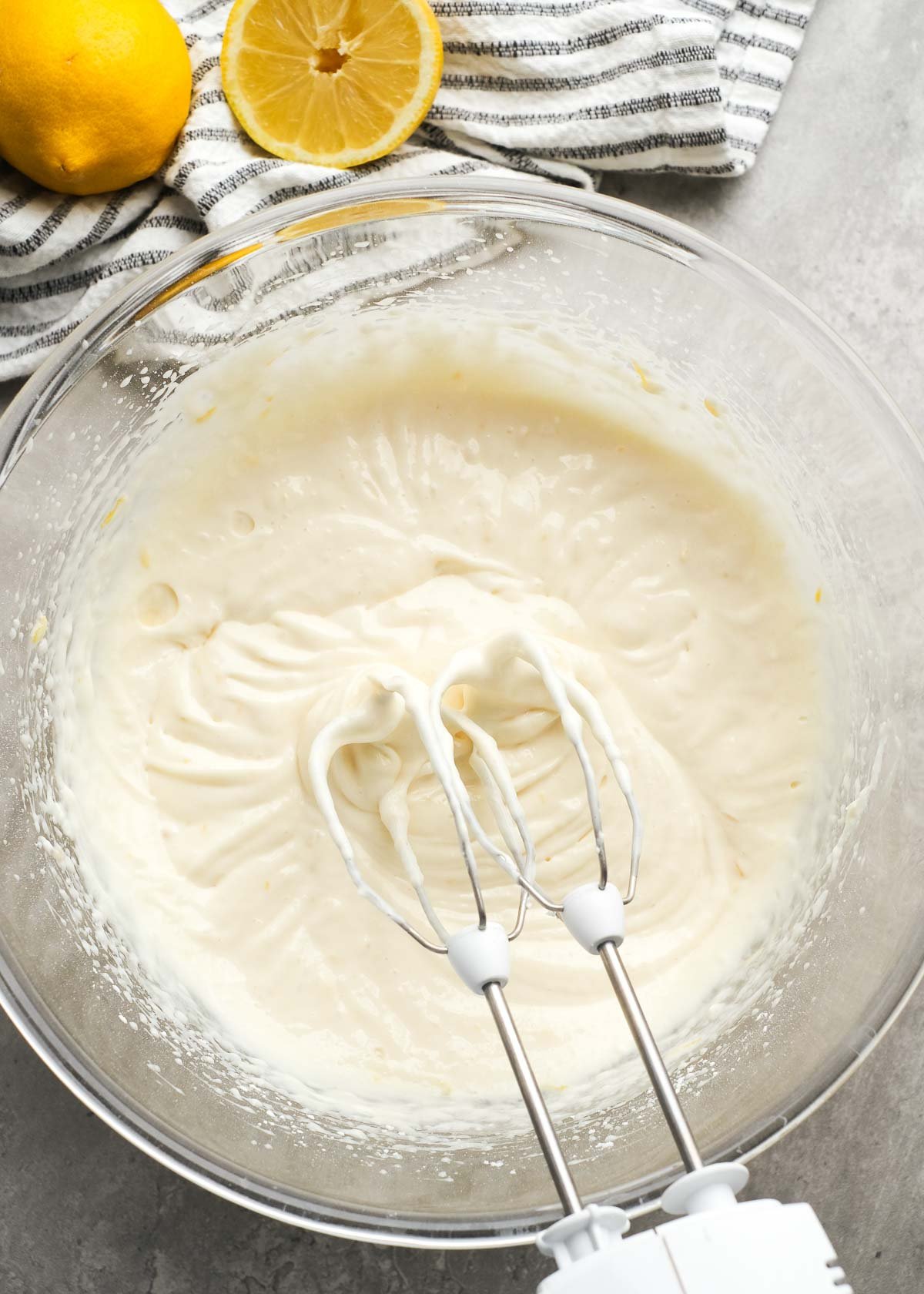 cream cheese, lemon juice, lemon zest, vanilla extract, powdered sugar, and lemon extract beaten in a glass bowl with an electric mixer