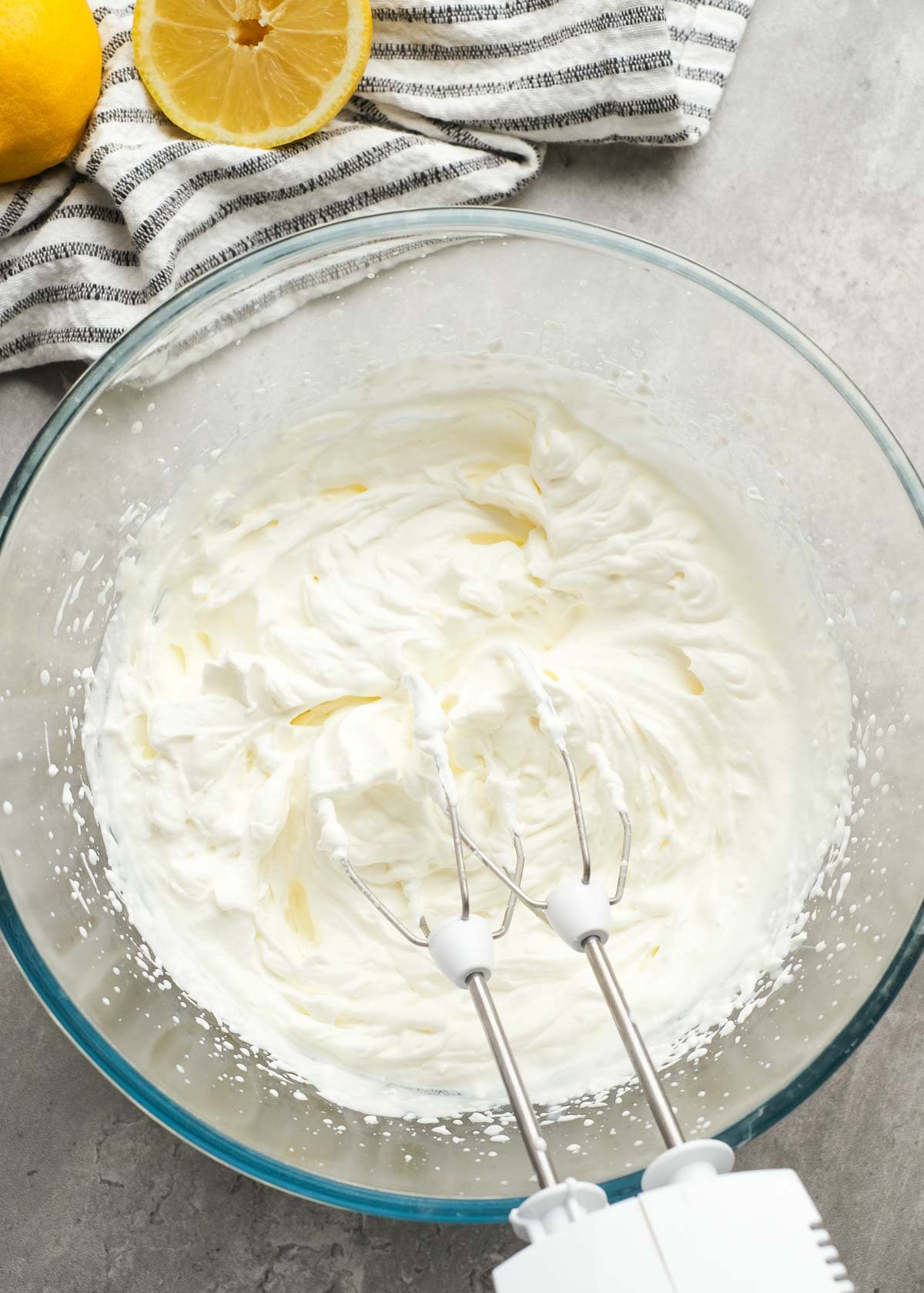 heavy cream beaten into whipped cream with stiff peaks in a glass bowl using an electric mixer