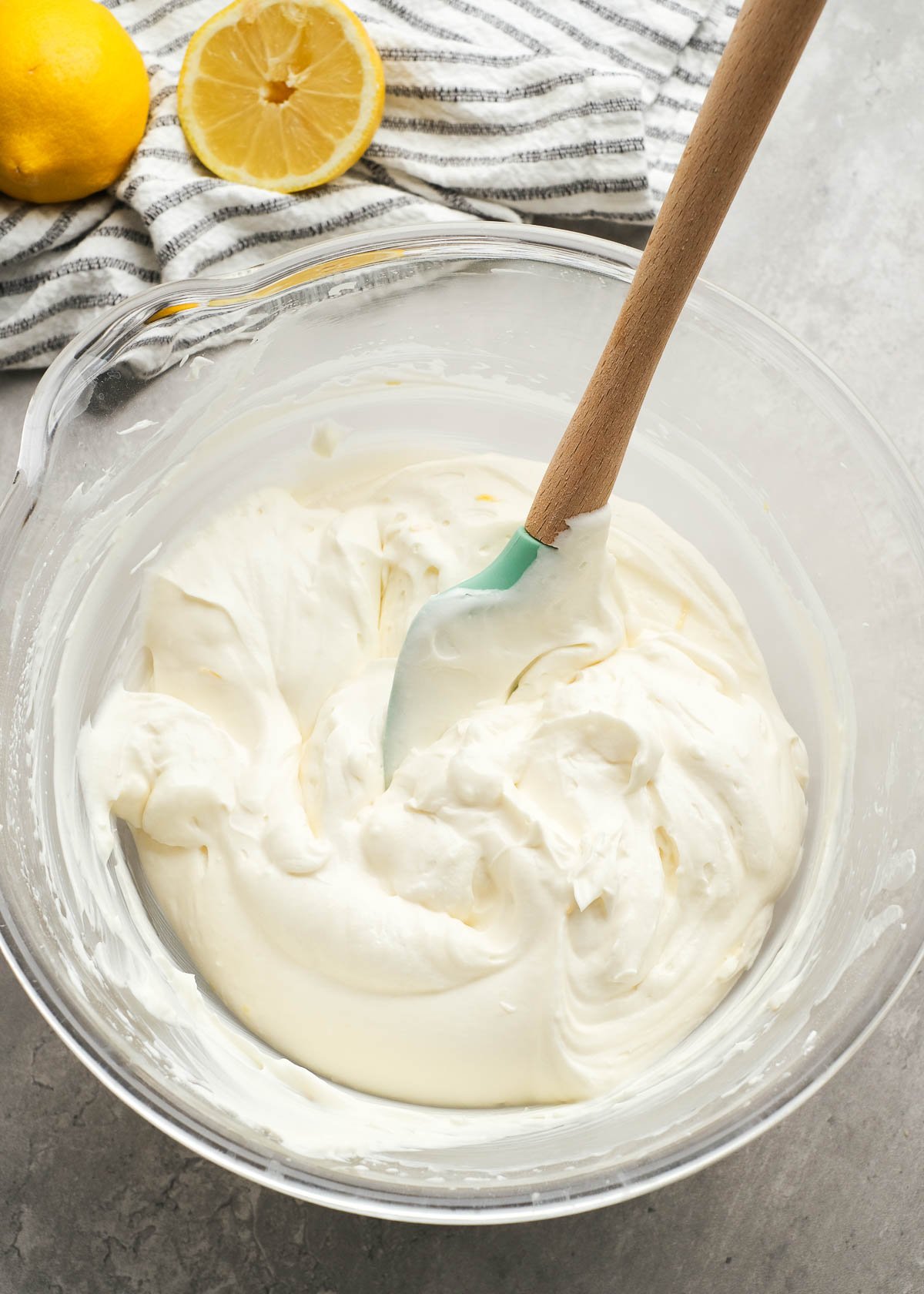 whipped cream being folded into a flavored cream cheese mixture to create a lemon cheesecake filling