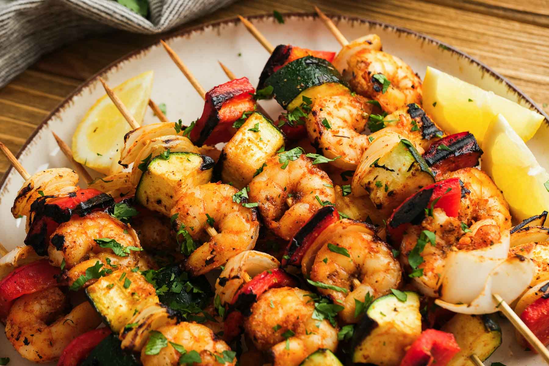 horizontal view of a plate loaded with ten juicy grilled shrimp kabobs with veggies