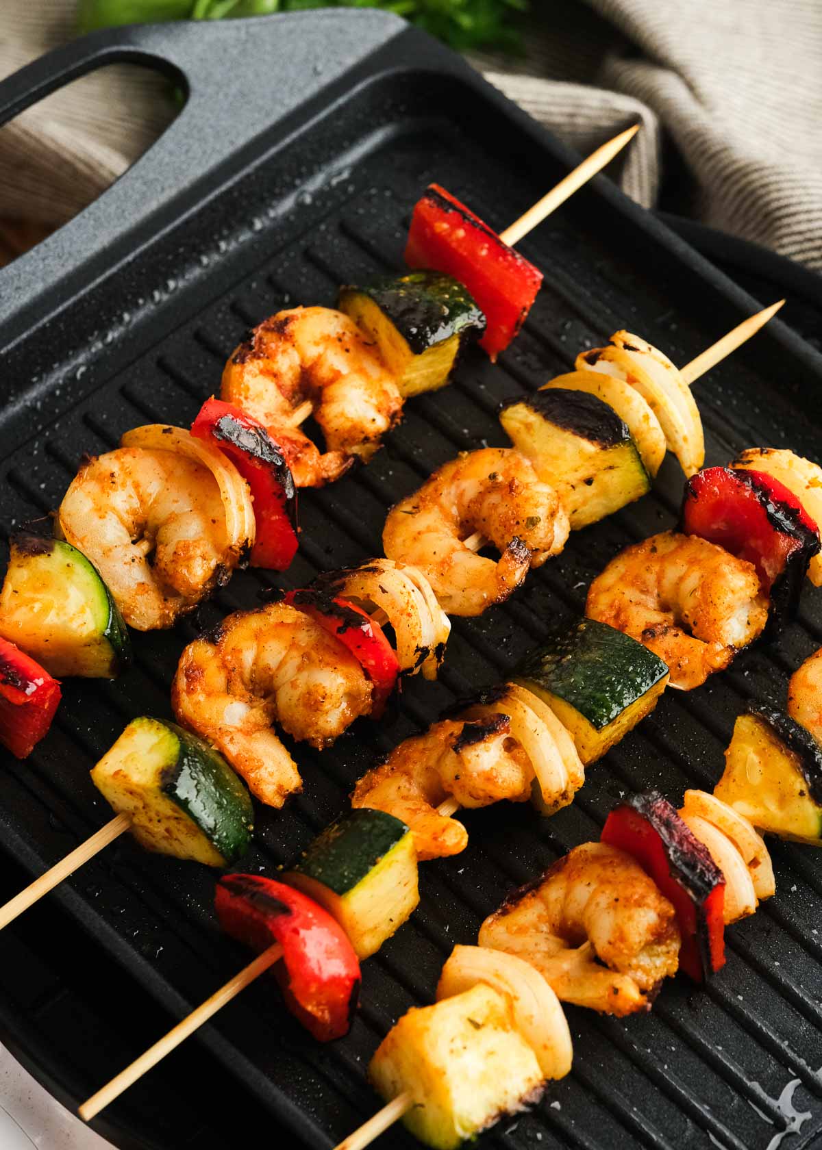 four shrimp kabobs cooking on a grill