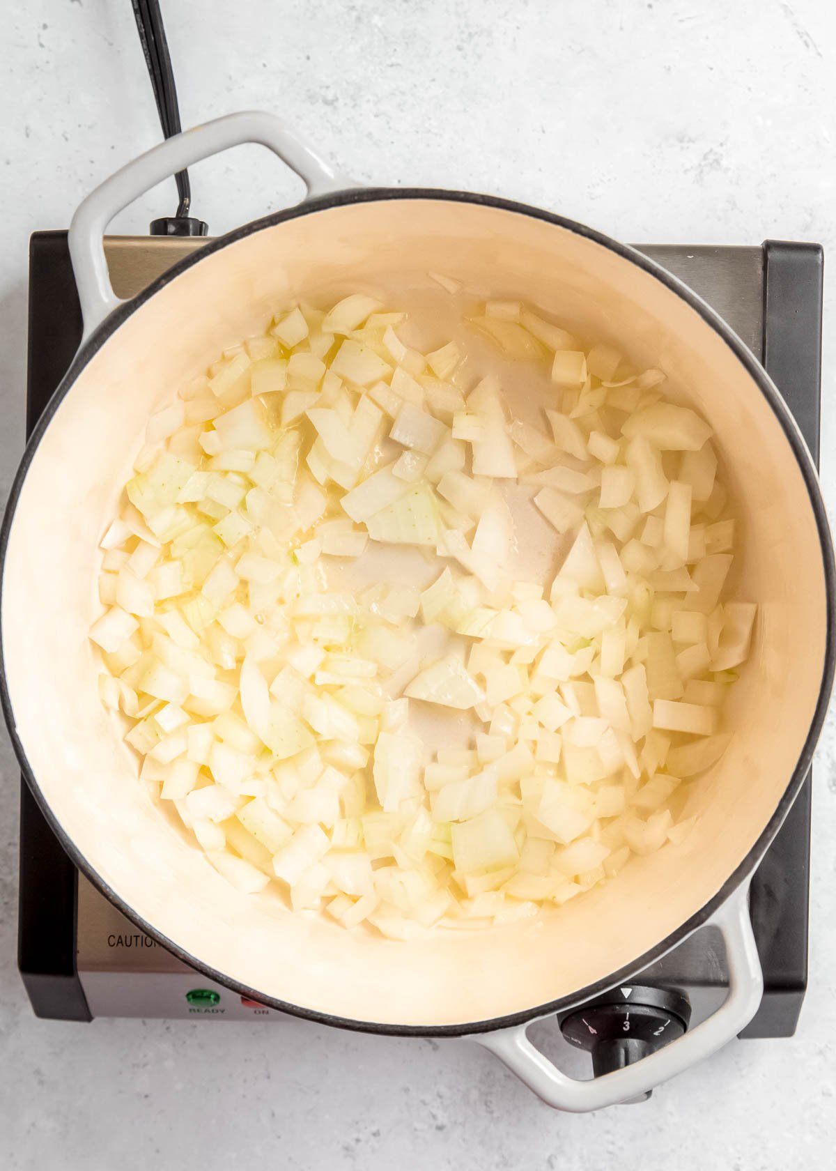 onion being sauteed in white pan