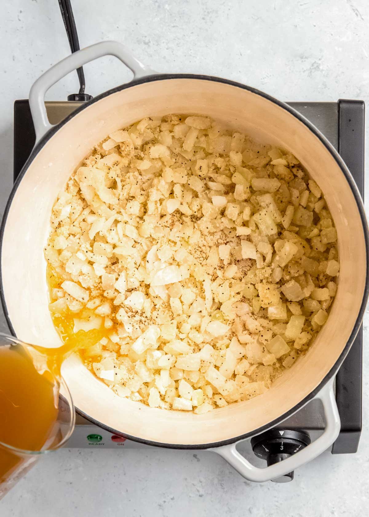 overhead image of chicken broth being added to pan