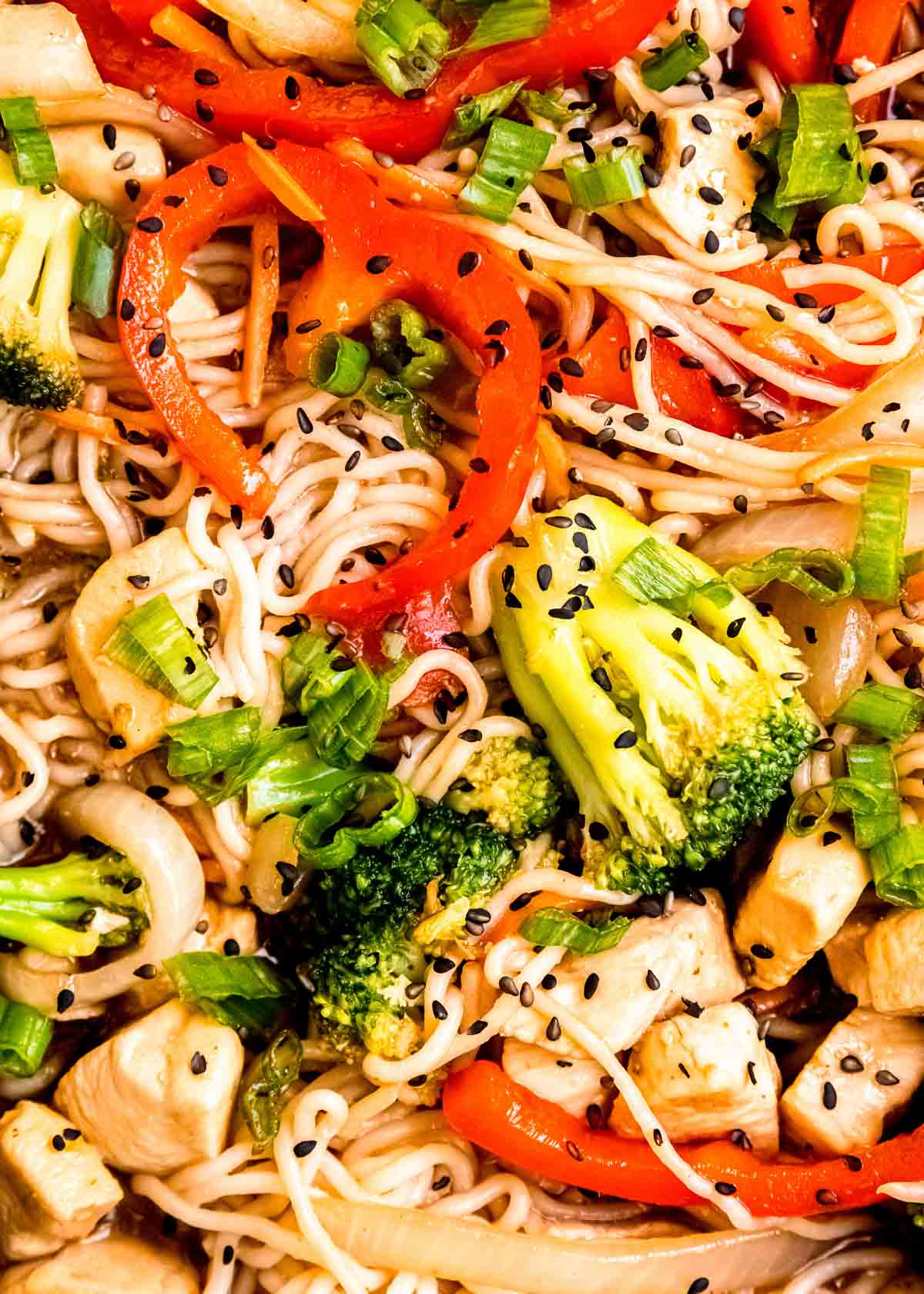 closeup overhead view of shirataki noodle stir fry with chicken, red peppers, broccoli, and onion