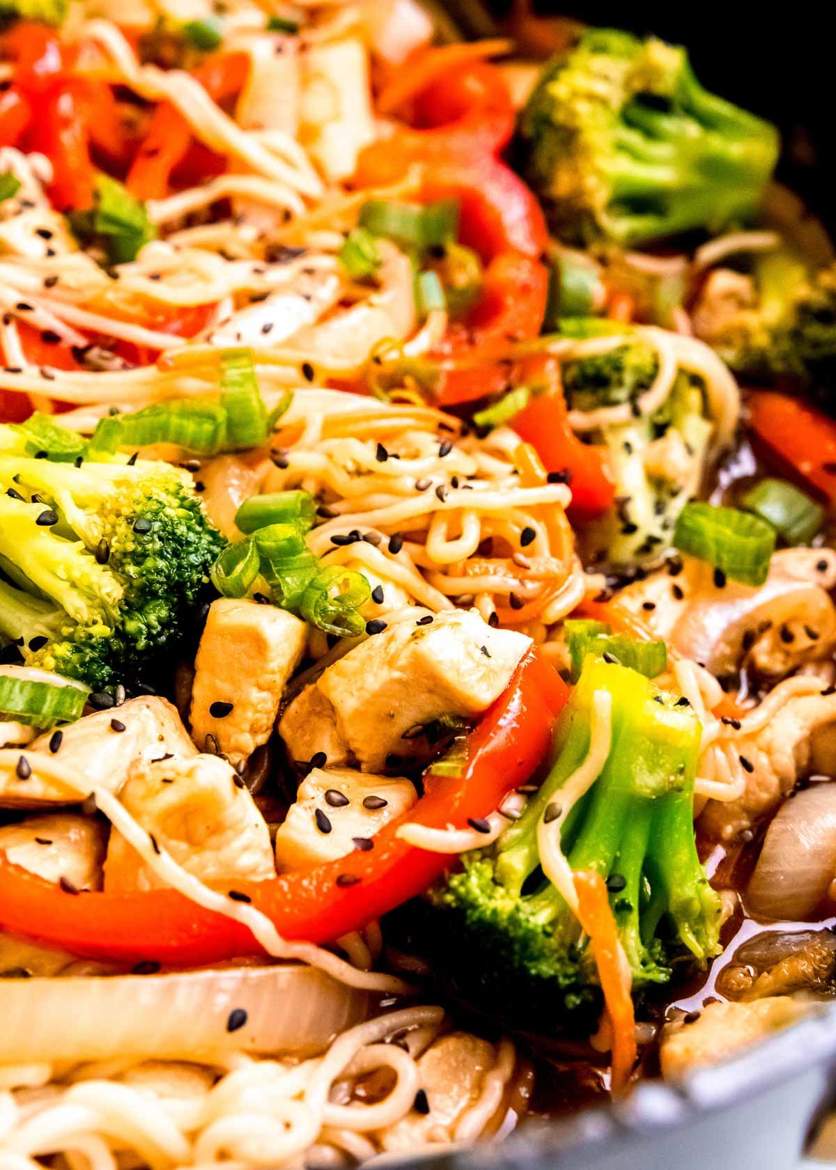 juicy chicken, tender shirataki noodles, red bell peppers, broccoli florets covered in stir fry sauce in a skillet