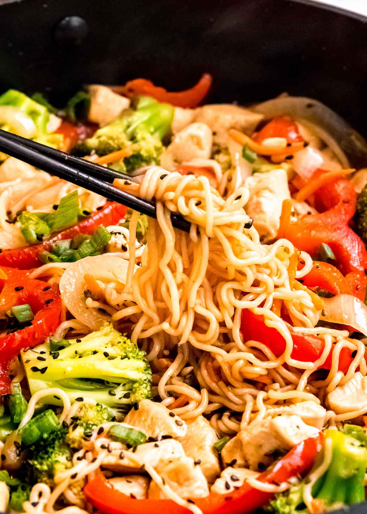 chopsticks picking up shirataki noodles in a skillet full of delicious chicken and veggie stir fry