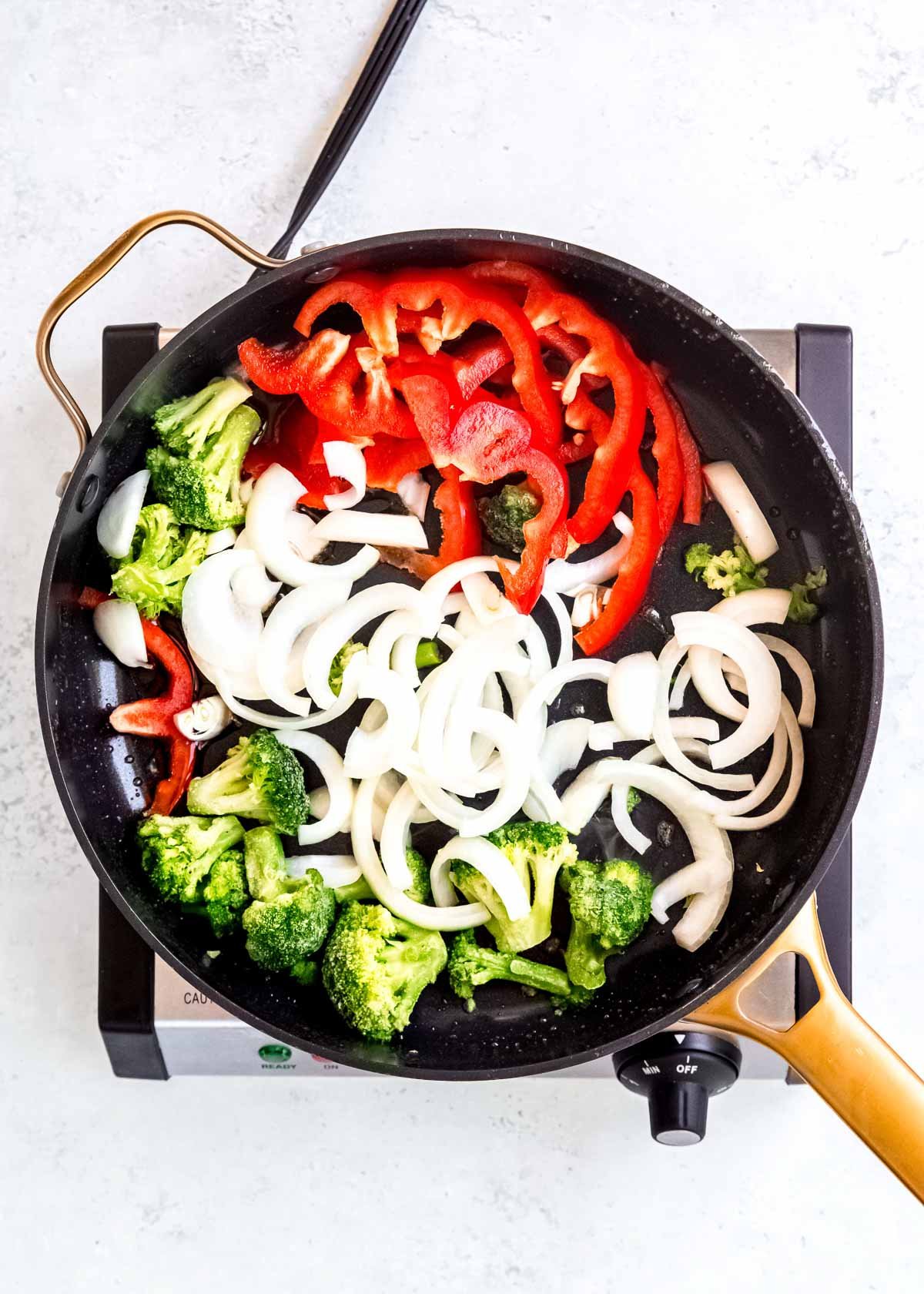frozen broccoli, sliced onion, and sliced red pepper in a skillet