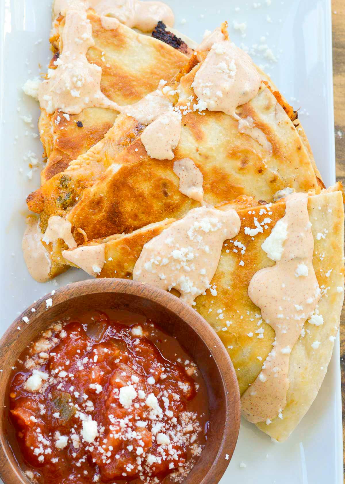 a cheesy taco bell chicken quesadilla copycat topped with creamy jalapeno sauce and a side of salsa