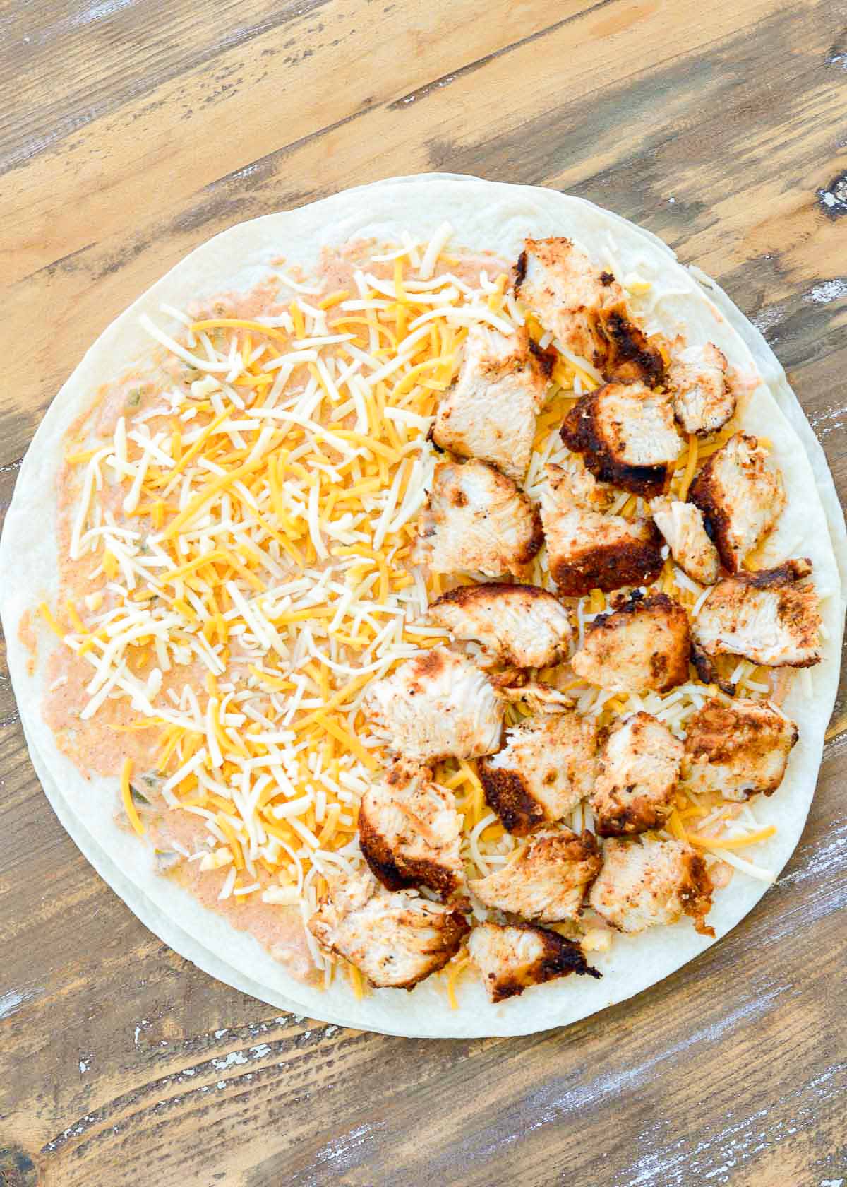 juicy sliced chicken arranged on half of a tortilla with jalapeno cream sauce and shredded cheese