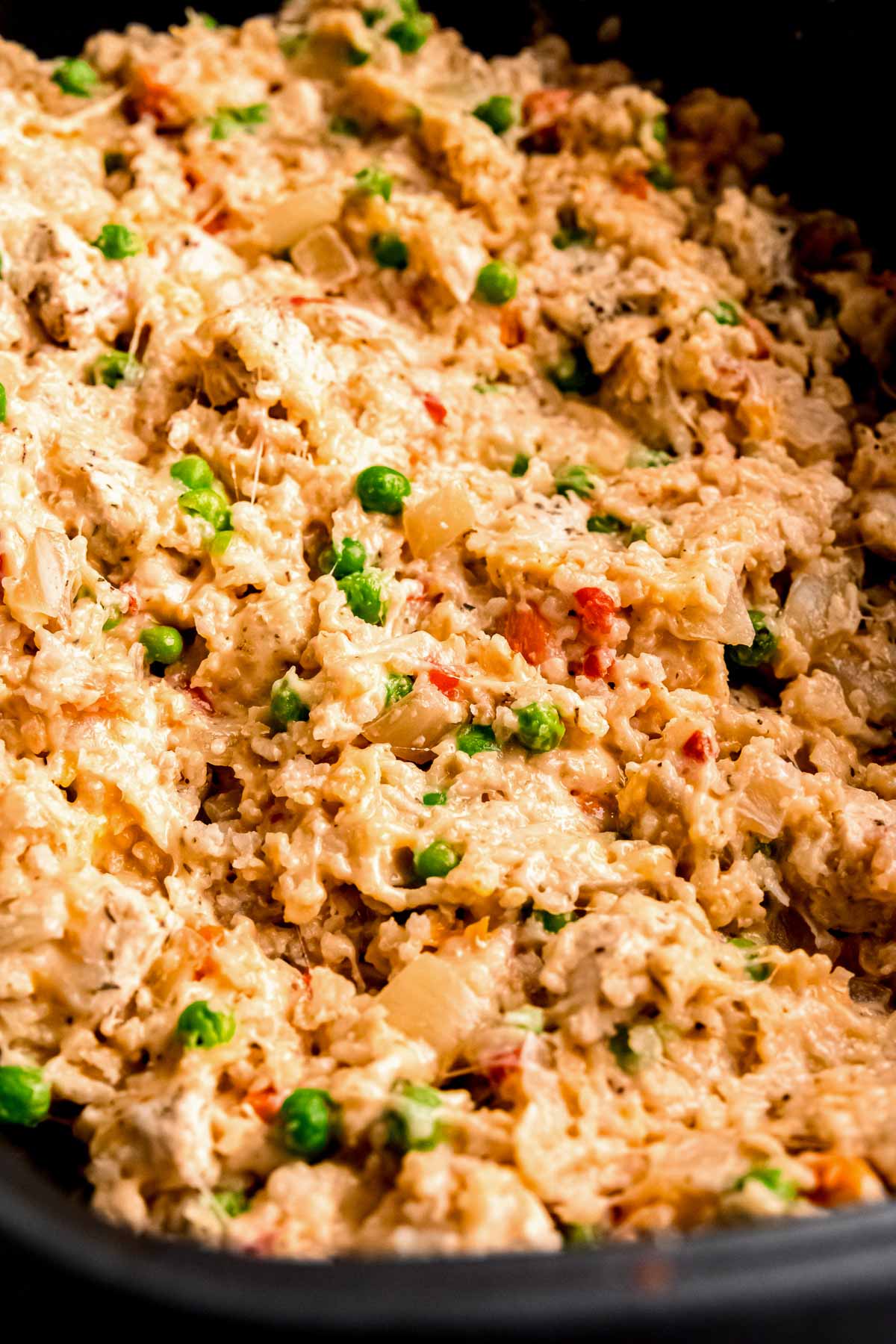 crockpot filled with cheesy chicken and rice with peas and carrots