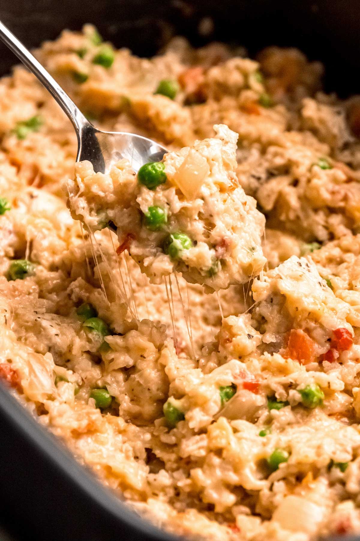 a cheesy bite of chicken and rice in a crockpot with peas and carrots