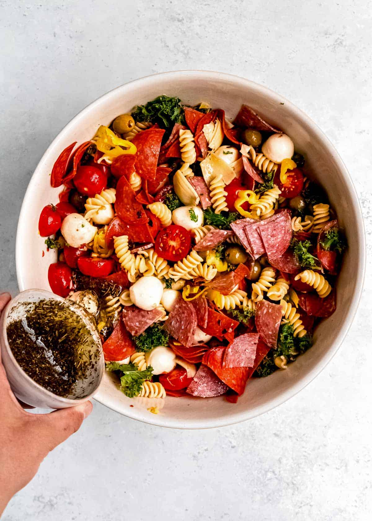 Italian vinaigrette poured over a pasta salad in a bowl