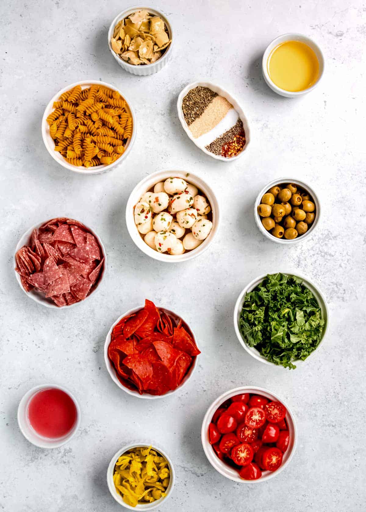 all ingredients needed for an italian pasta salad on a marble countertop