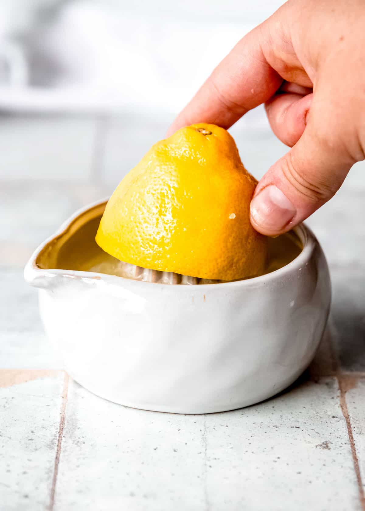 a hand juicing a lemon half