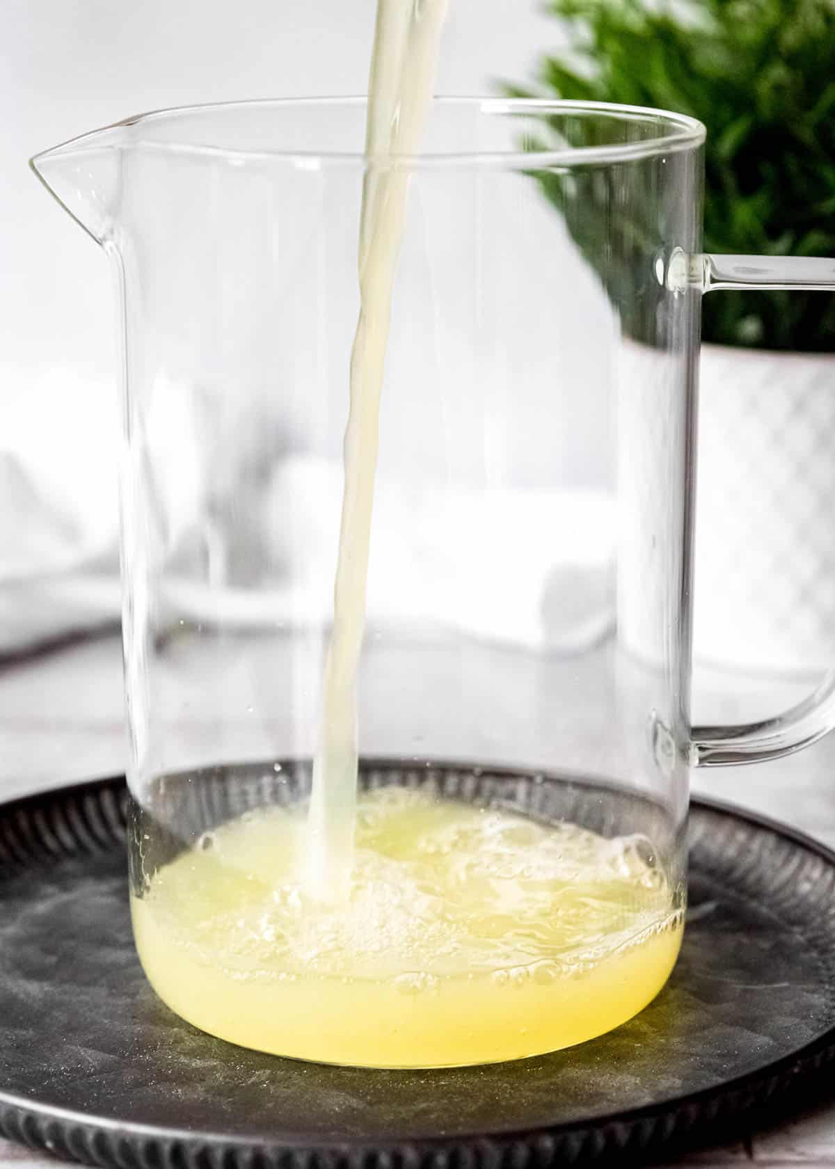 fresh lemon juice being poured into a pitcher
