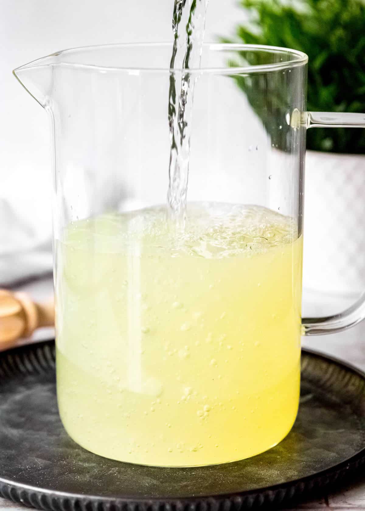 water pouring into a pitcher with lemon juice