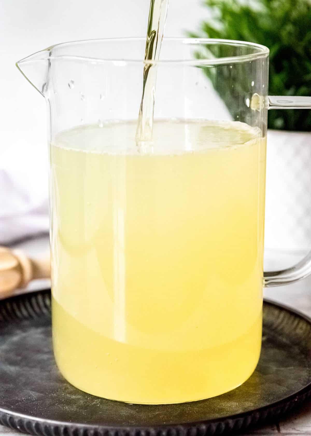 bourbon whiskey and peach schnapps pouring into a pitcher of homemade lemonade