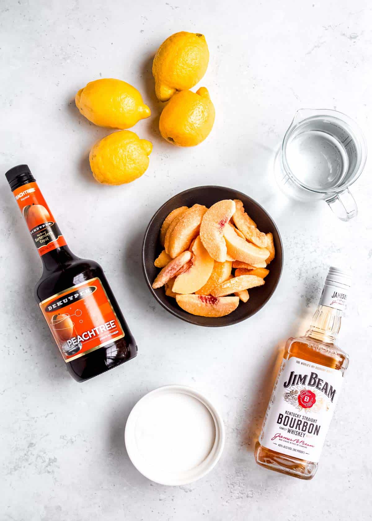 ingredients for a simple peach lemonade with bourbon on a countertop