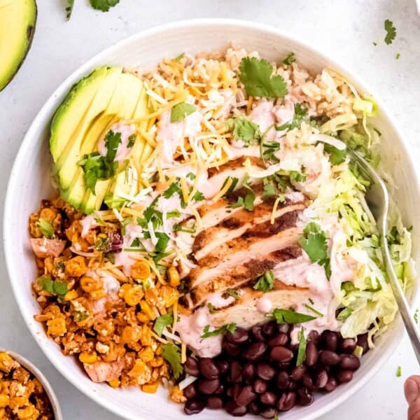 a white bowl filled with Mexican street corn burrito bowls