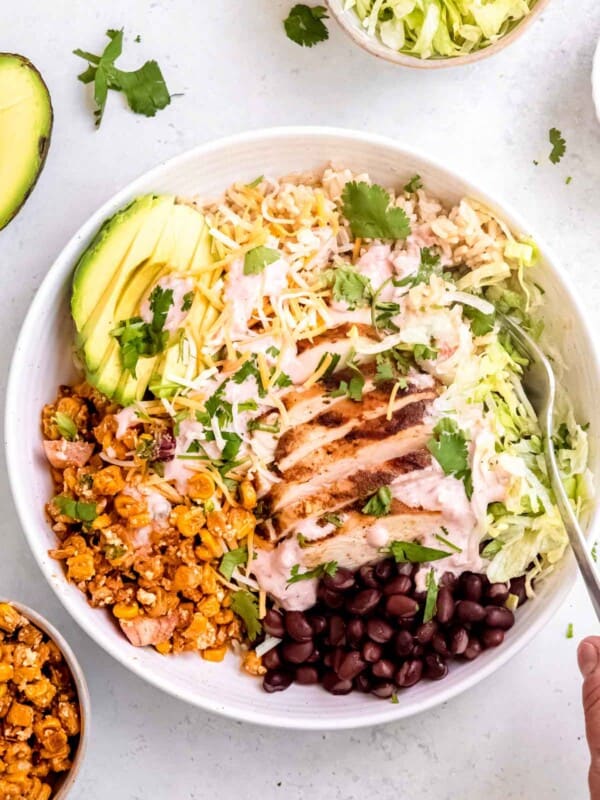 a white bowl filled with Mexican street corn burrito bowls