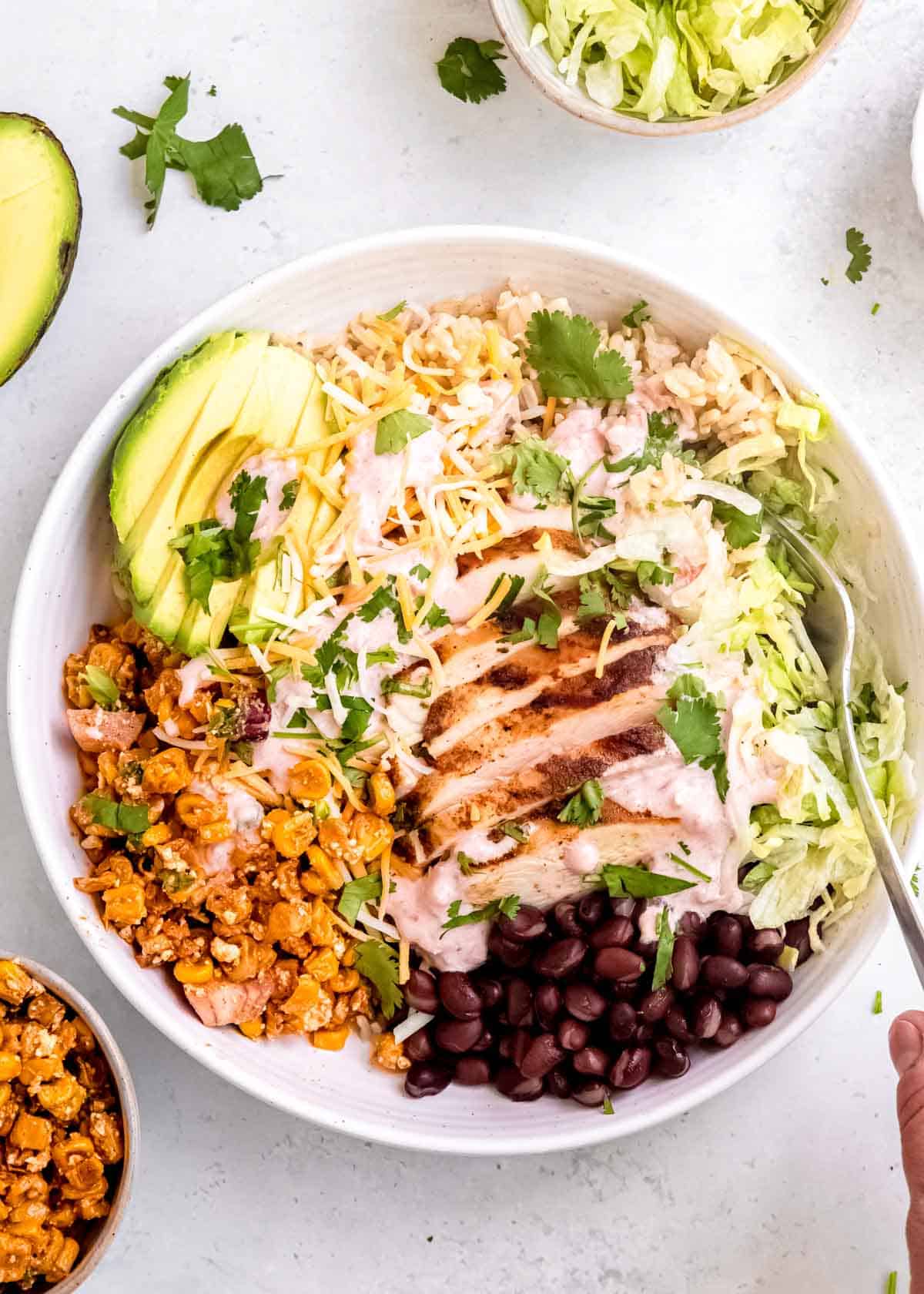 a white bowl filled with Mexican street corn burrito bowls