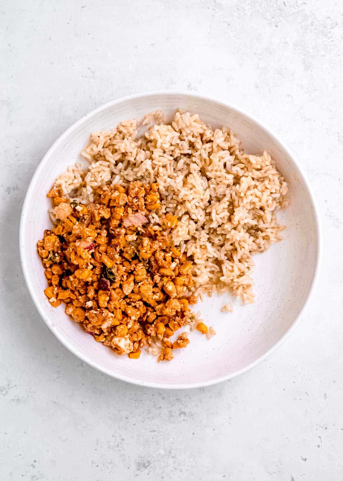 cooked brown rice and Mexican street corn salad in a white bowl