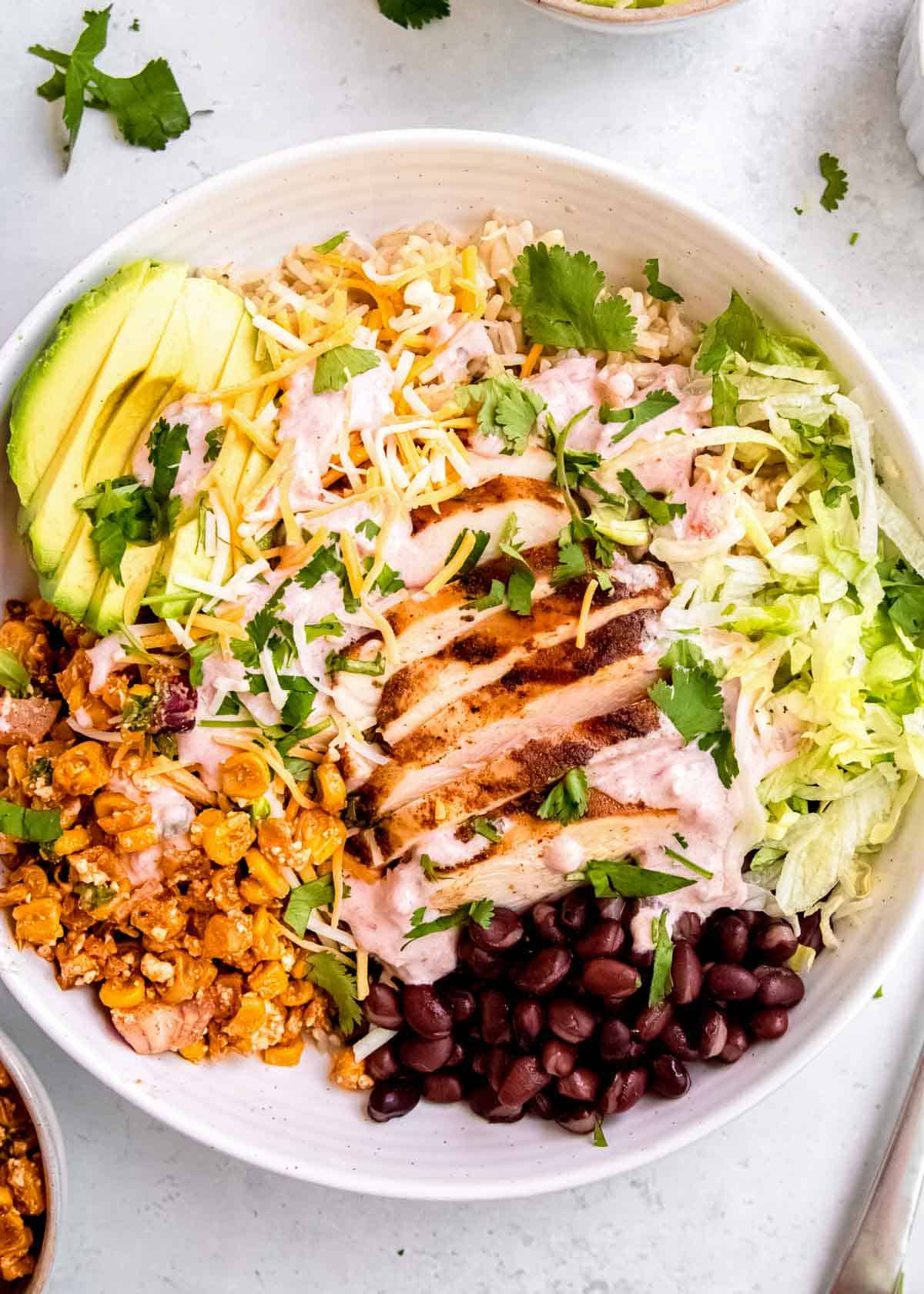 overhead shot showing a packed burrito bowl full of southwestern chicken, brown rice, and Mexican street corn salad