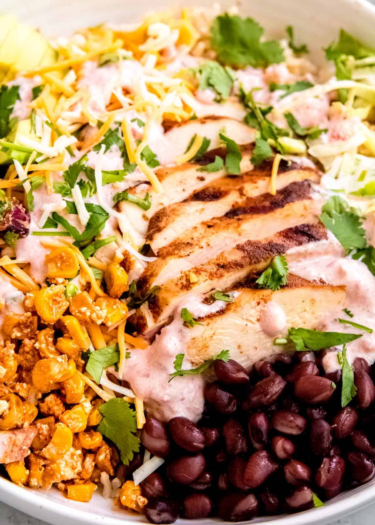 a burrito bowl filled with marinated chicken and mexican street corn