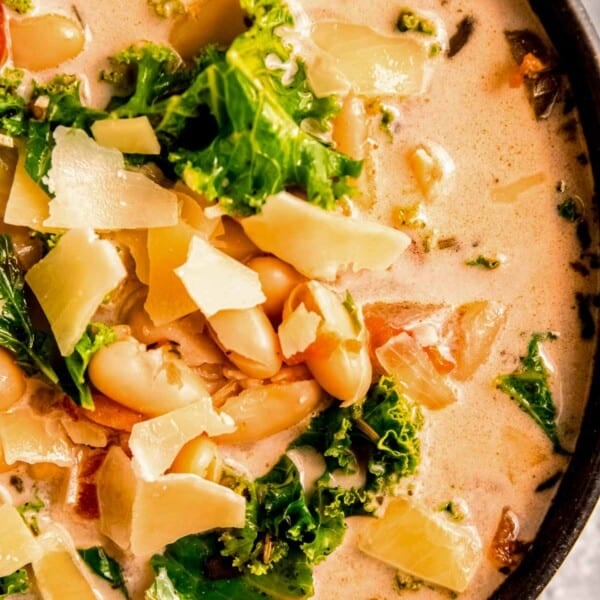 closeup shot of creamy tuscan soup with white beans, kale, and parmesan