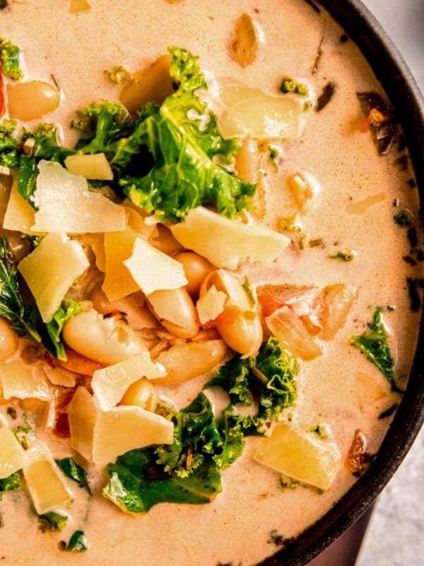 closeup shot of creamy tuscan soup with white beans, kale, and parmesan