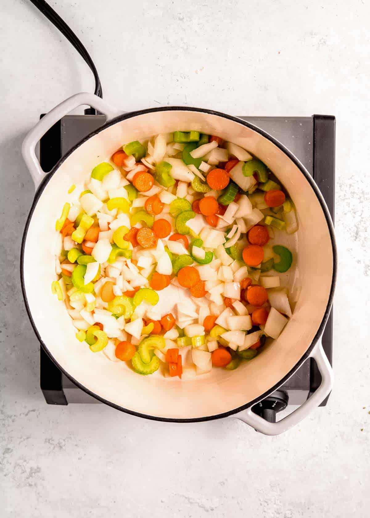 chopped onions, carrots, and celery sauteing in oil in a dutch oven