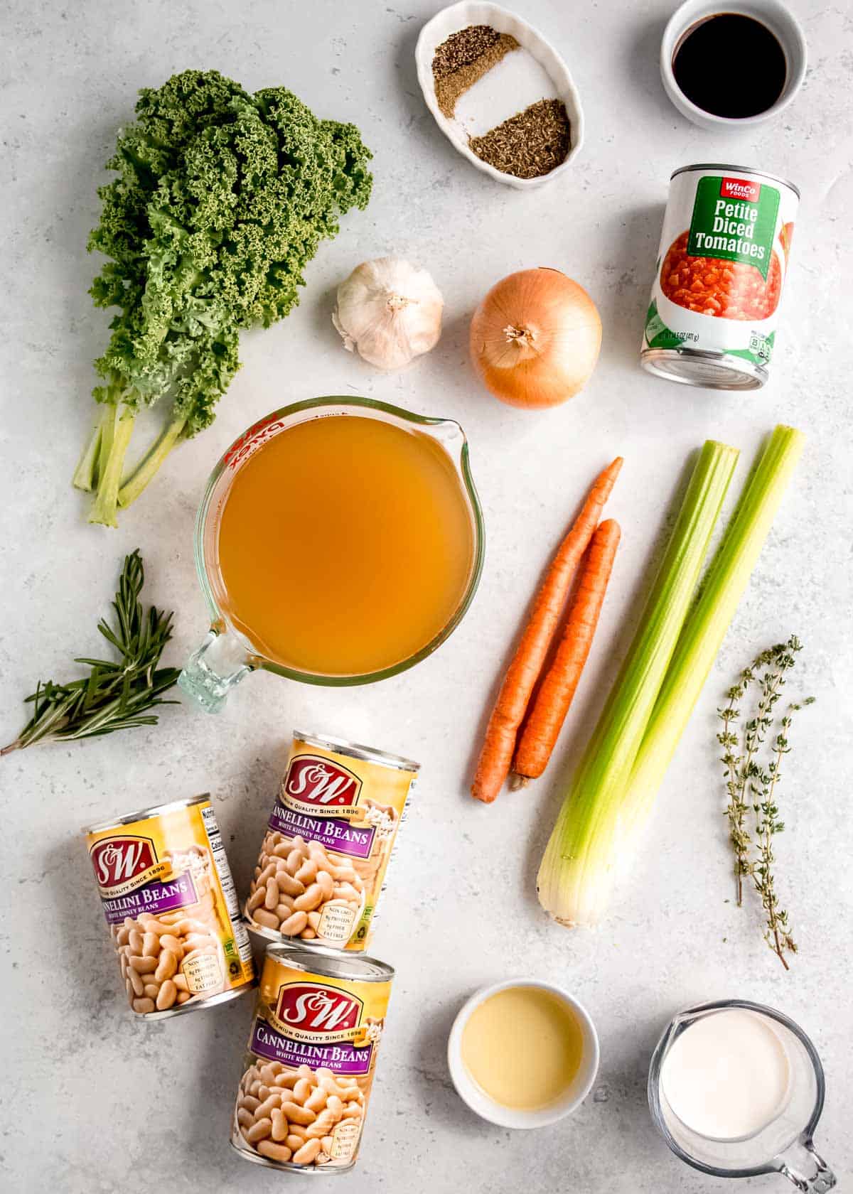 all ingredients needed for tuscan white bean soup on a white countertop