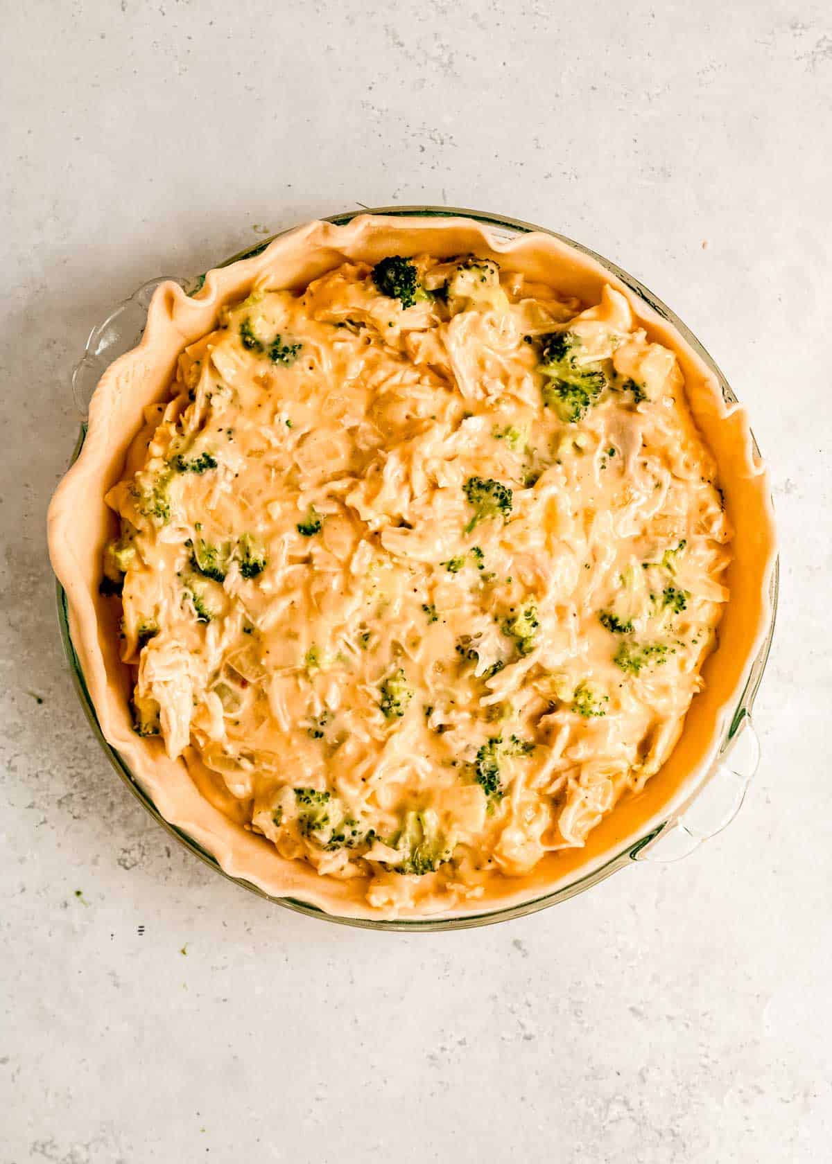 broccoli cheddar chicken filling poured onto a crust in a pie pan