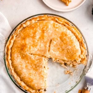 a glass pie pan with a broccoli cheddar chicken pot pie; two slices are missing and on white plates