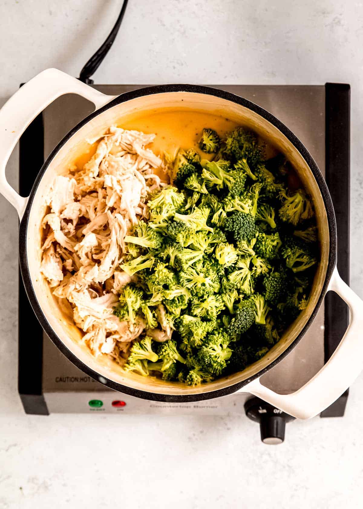 broccoli florets and shredded chicken in a cheese sauce in a pot